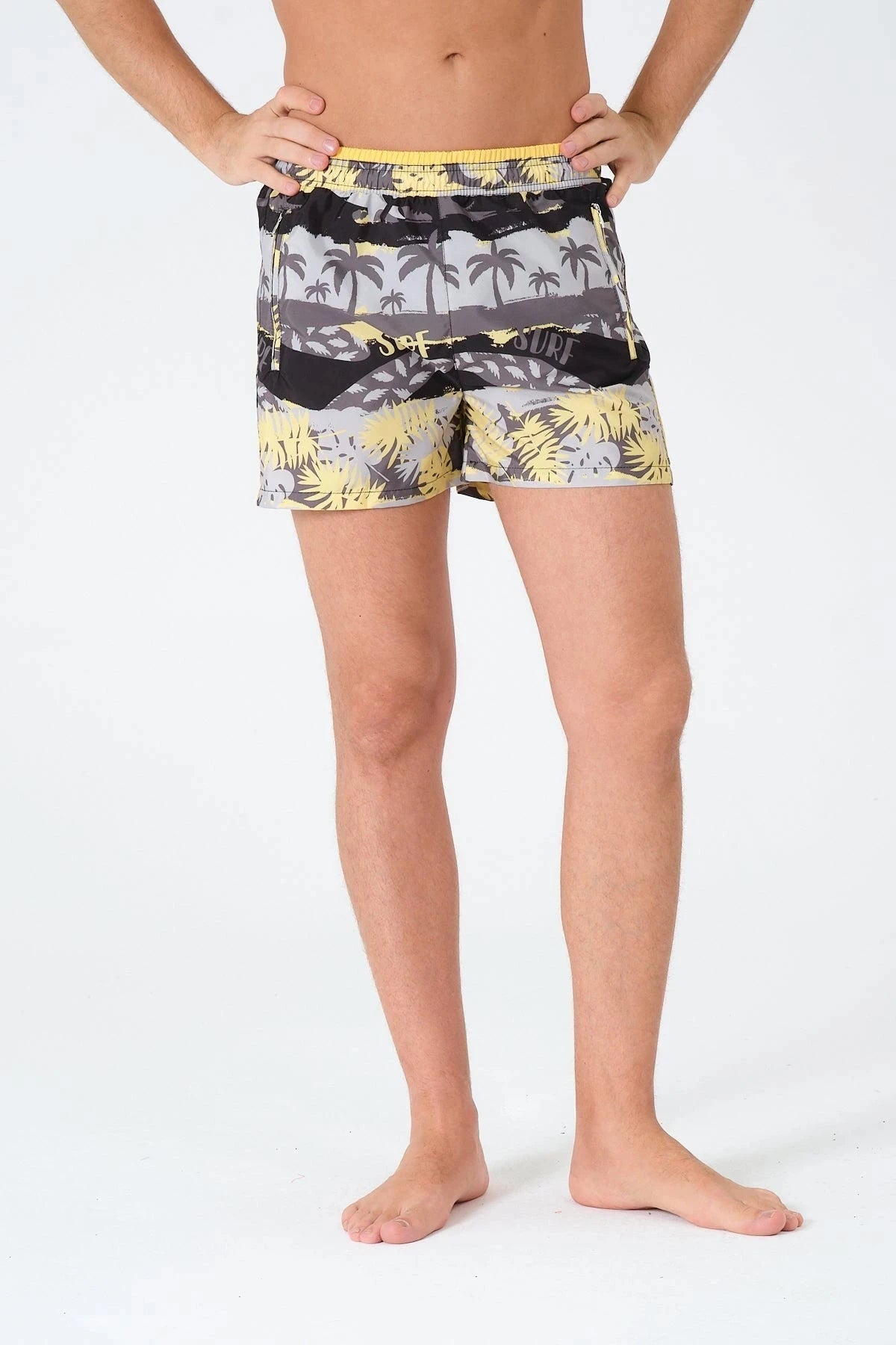 Close-up of man wearing tropical print swim trunks, front view.