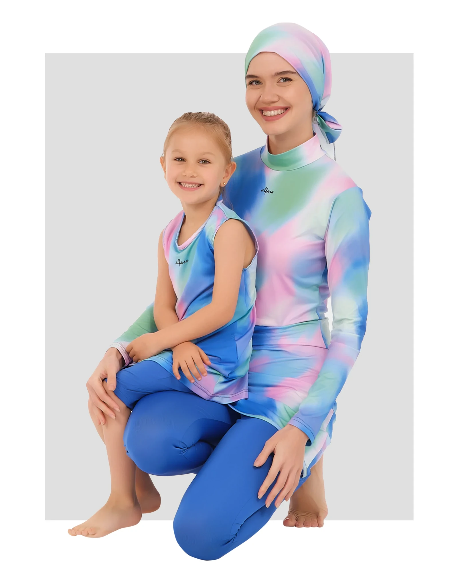 Mother and daughter in matching tie-dye burkini sets, smiling.