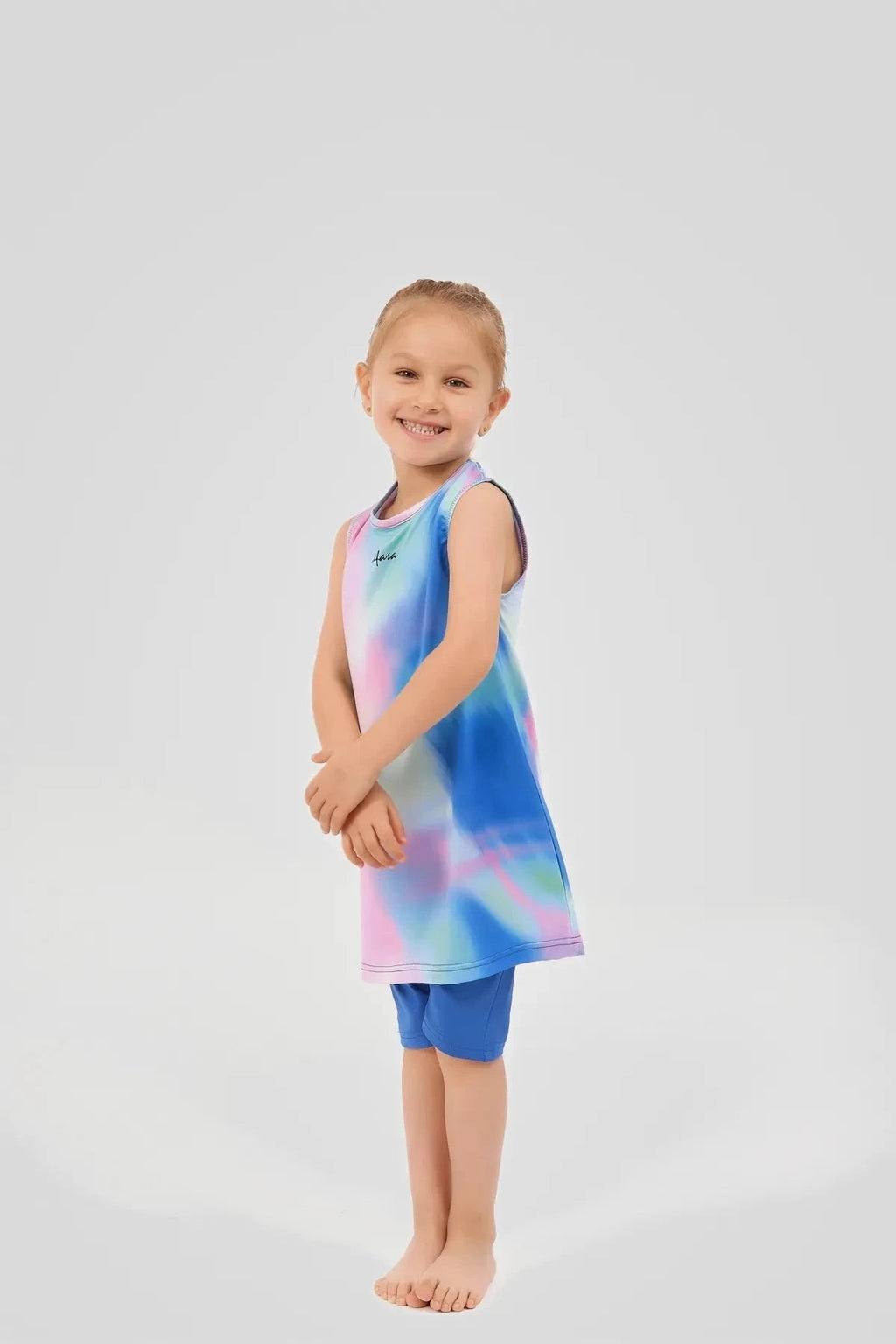 Young girl in a colorful tie-dye swim dress and blue leggings.