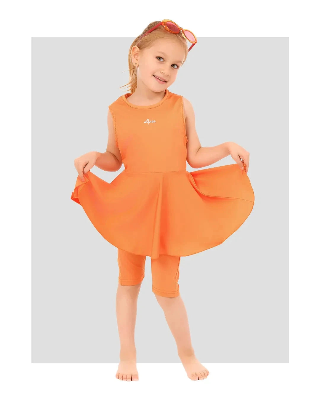 Young girl in orange modest swim dress and leggings, front view.