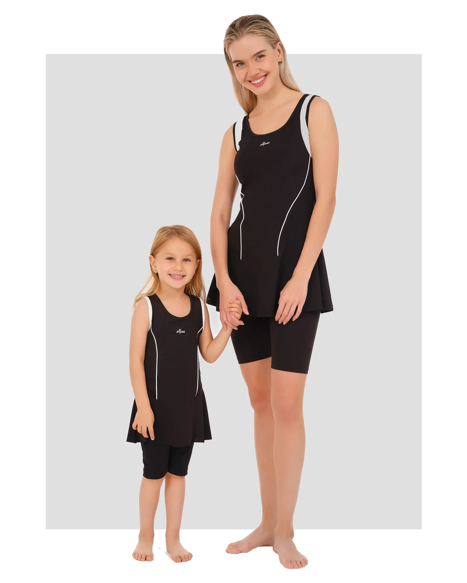 Mother and daughter in matching black modest swimwear with white piping.