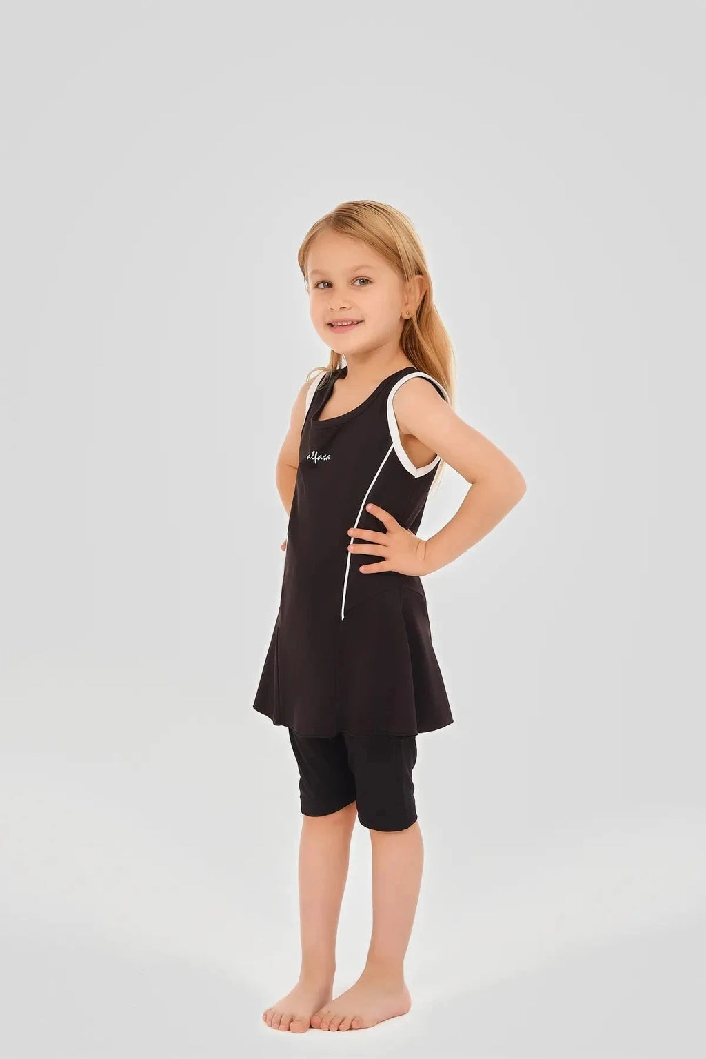 Young girl in black modest swim dress with white piping and black shorts.