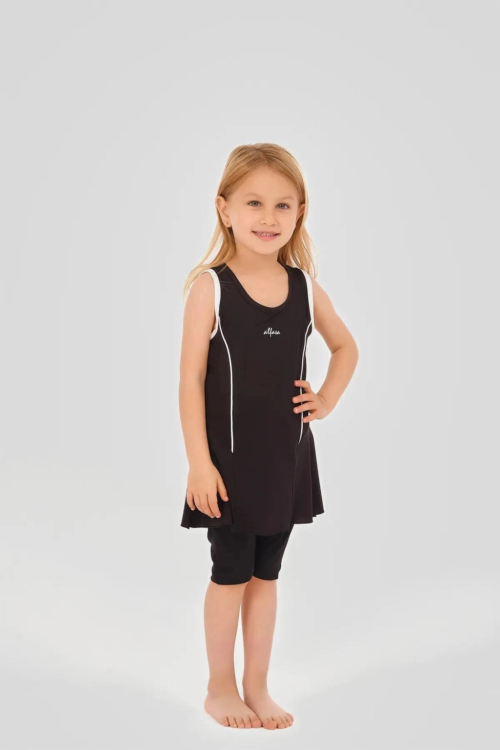 Young girl in black modest swim dress with white piping and black shorts.