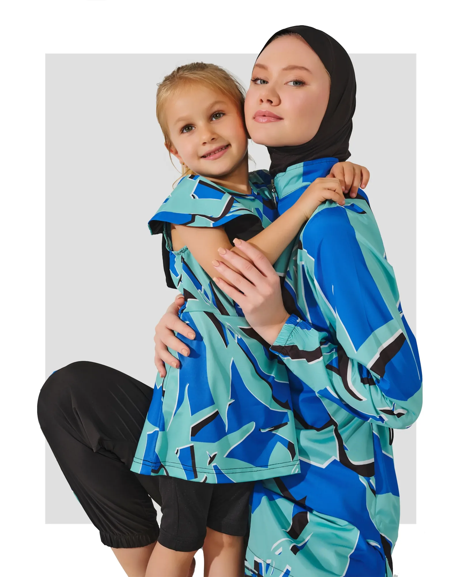 Blue abstract print burkini dress with flutter sleeves worn by a child, next to a woman.