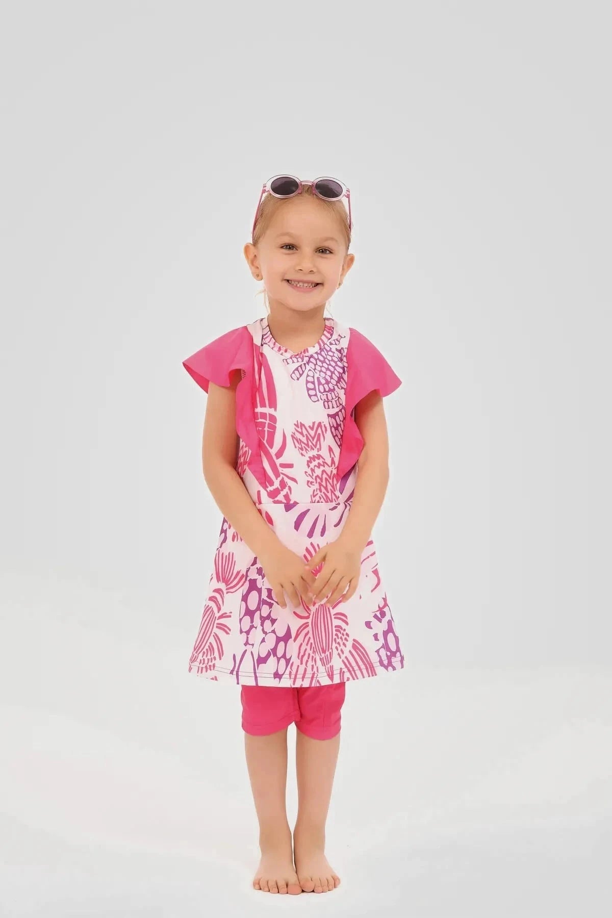 Young girl in pink floral print burkini dress and pink leggings