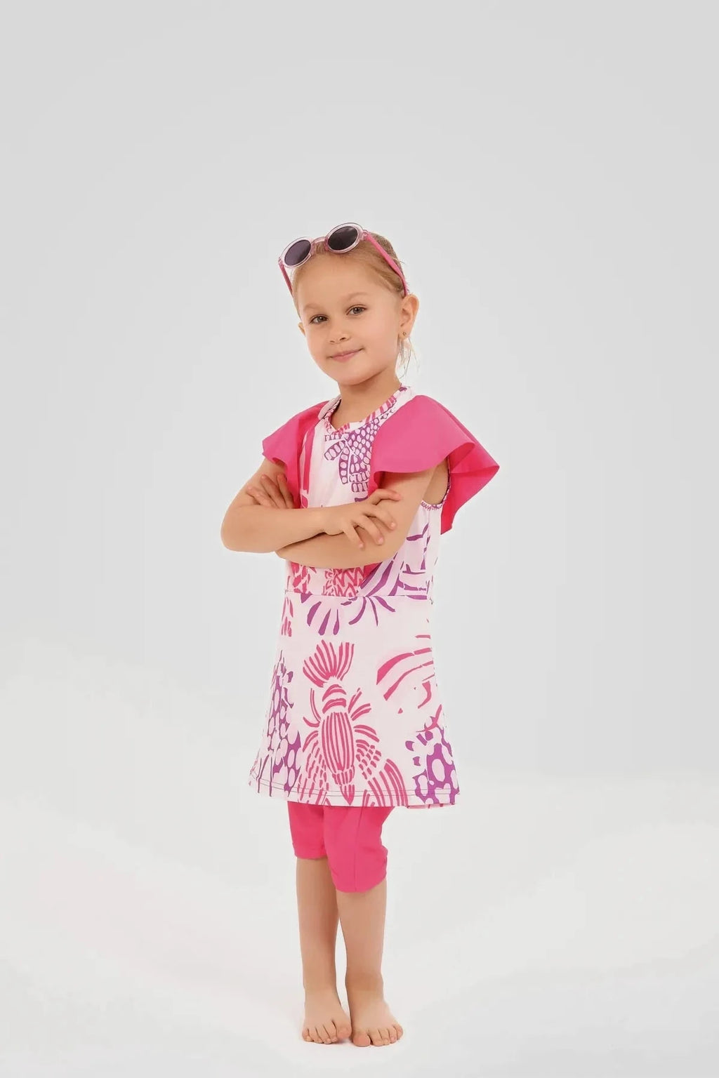 Young girl in pink floral print burkini dress with arms crossed