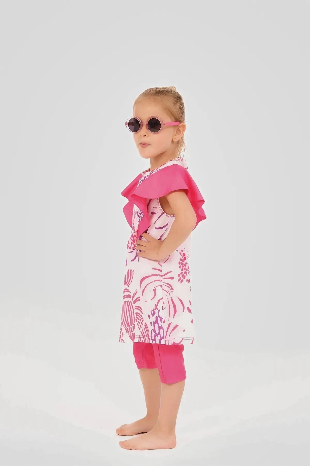 Side view of young girl in pink floral print burkini dress