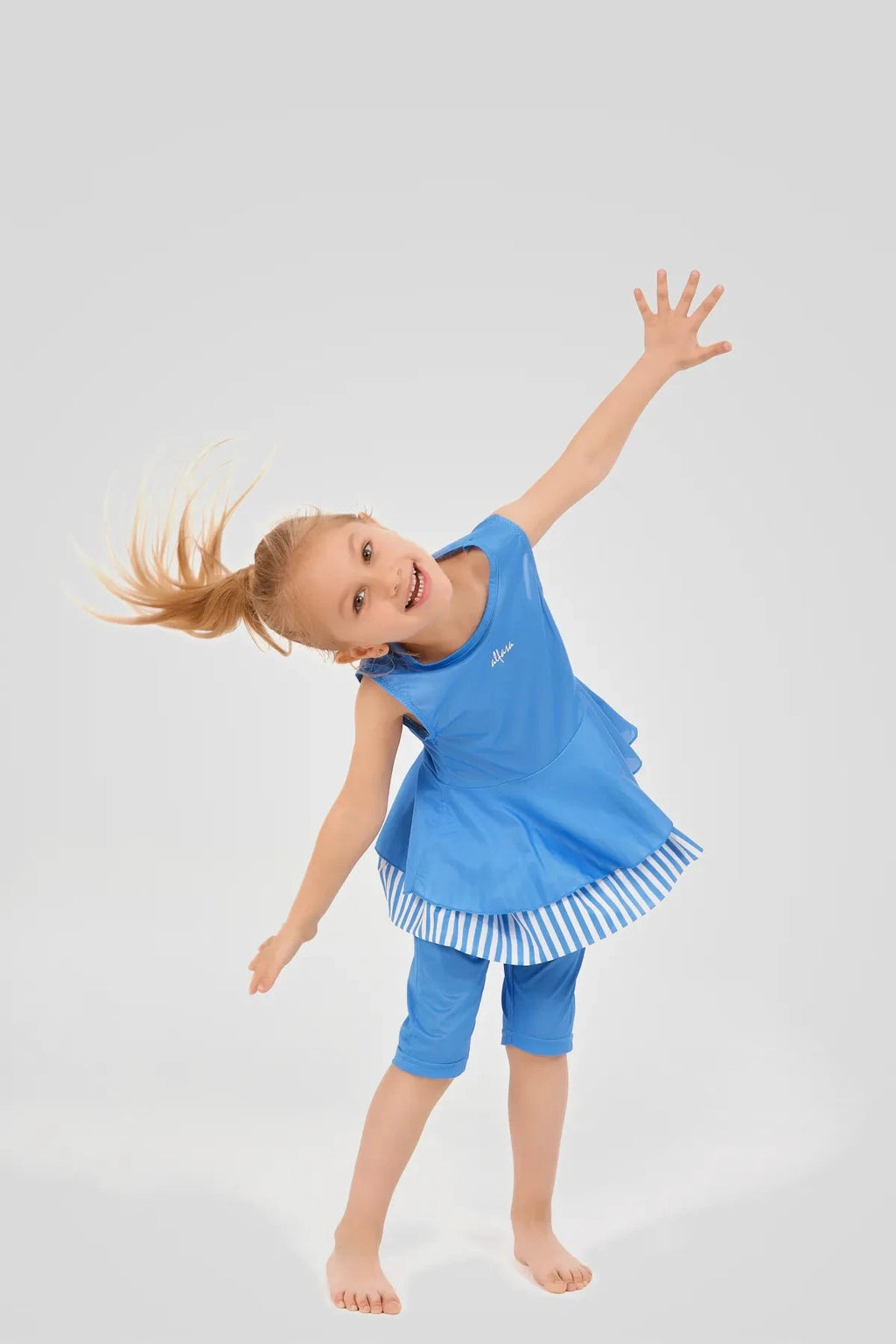 Girl in blue striped modest swim dress in a playful pose.