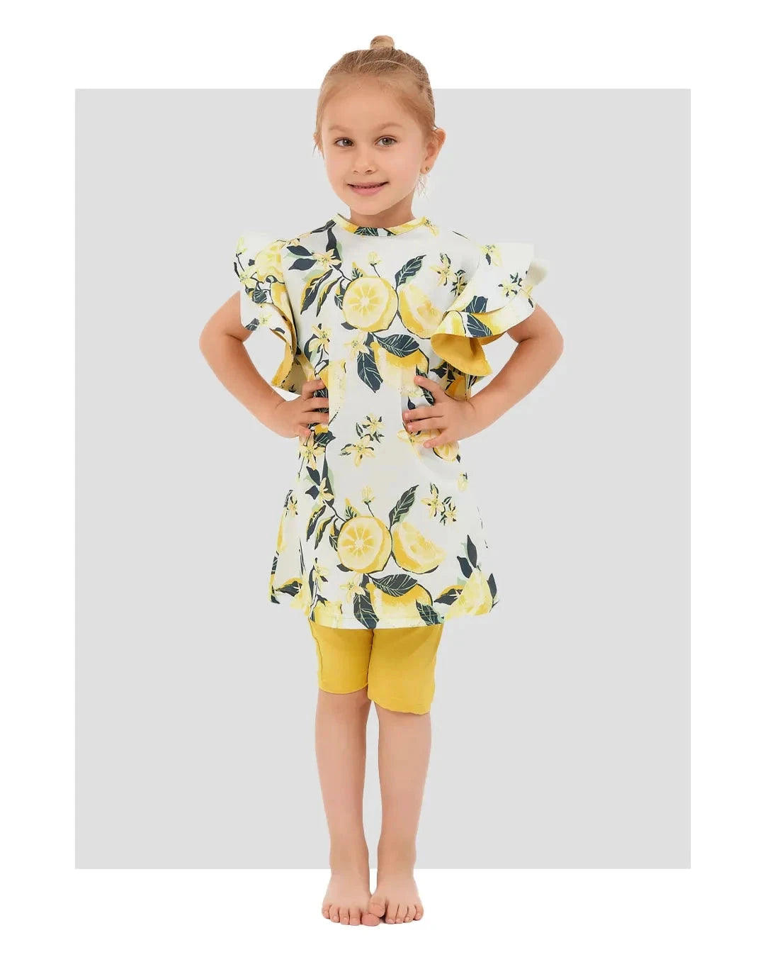 Young girl in lemon print modest swim dress and yellow shorts