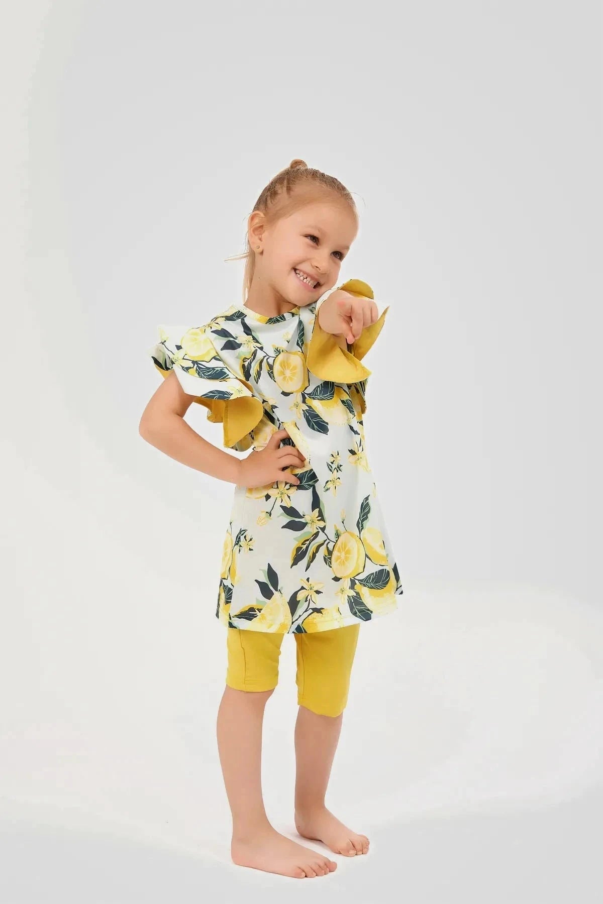 Girl in lemon print modest swimwear pointing and smiling