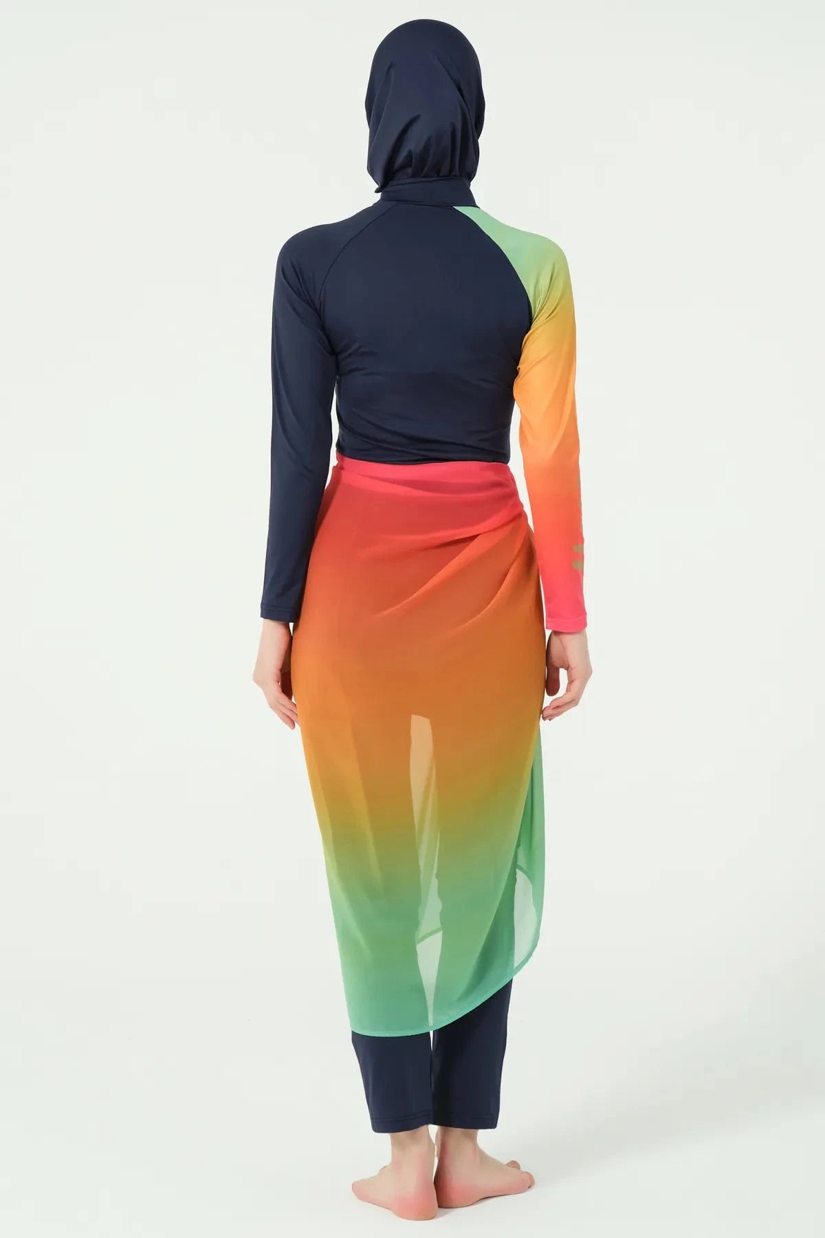 Model in gradient sarong over navy modest swimwear, back view.