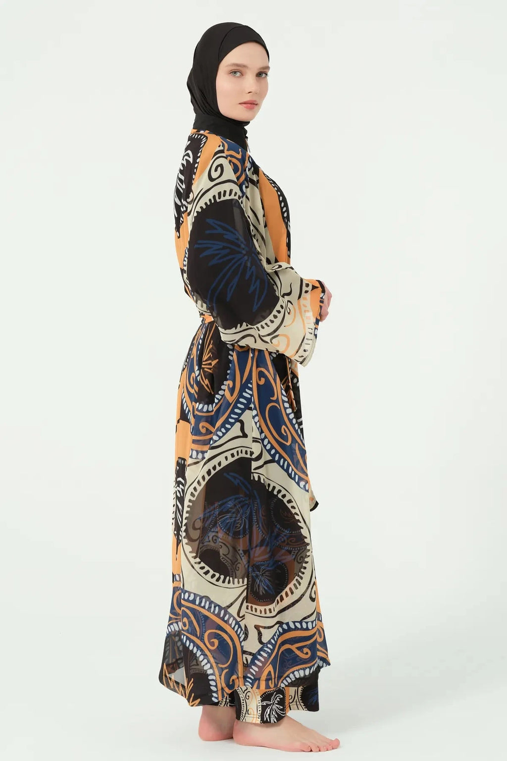 Model in abstract print sheer kimono with tie belt, profile view.