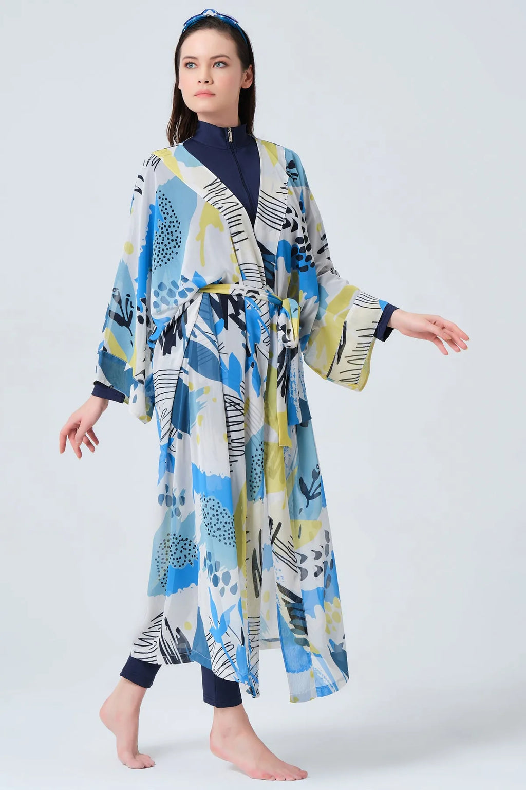 Woman walking in blue and yellow printed kimono swimwear, side view.