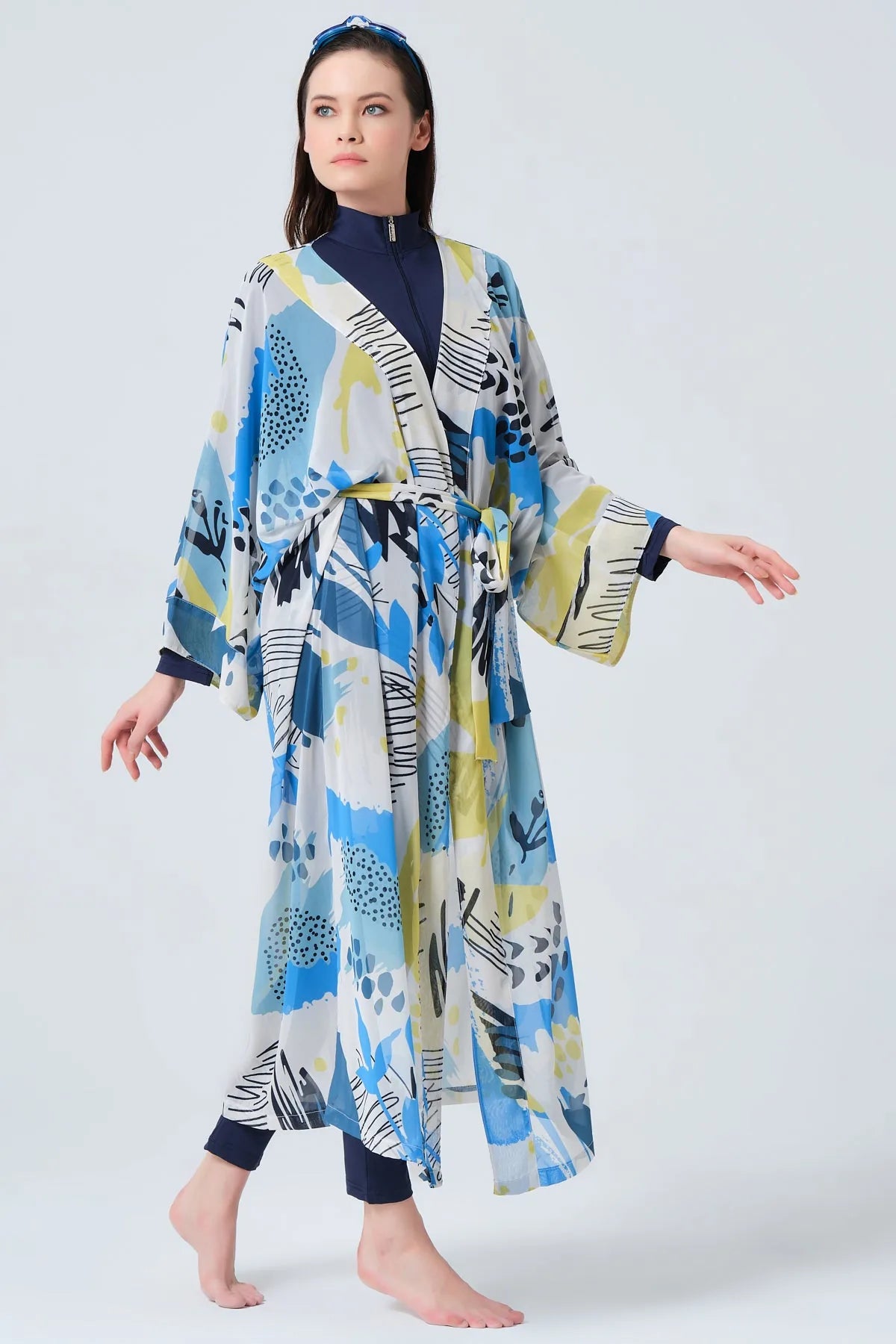 Woman walking in blue and yellow printed kimono swimwear, side view.