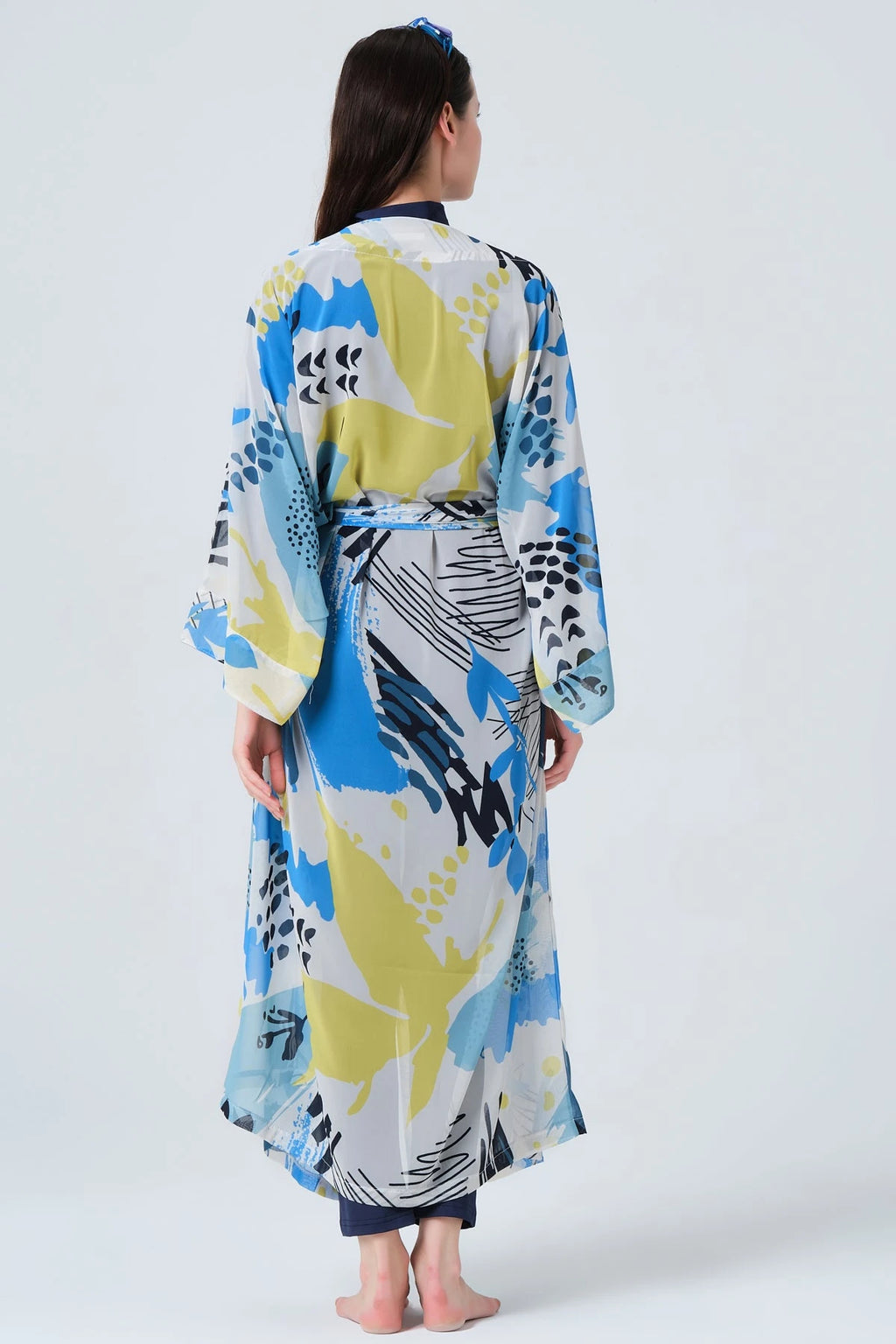 Woman in blue and yellow printed kimono swimwear, full back view.