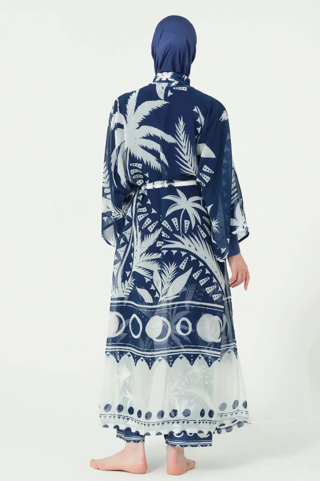 Woman in navy and white tropical print kimono, back view with tied belt.