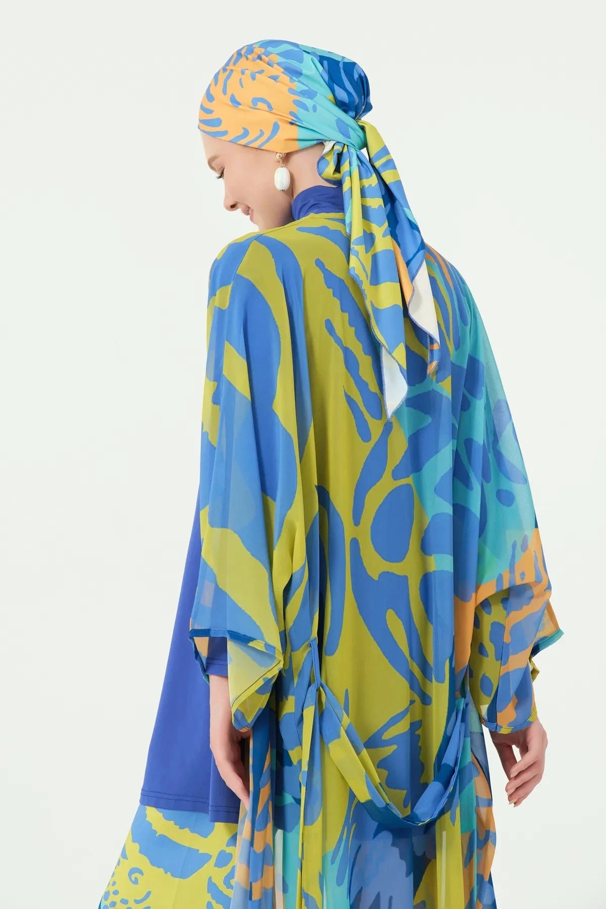 Woman in tropical print kimono and head covering, back detail view.