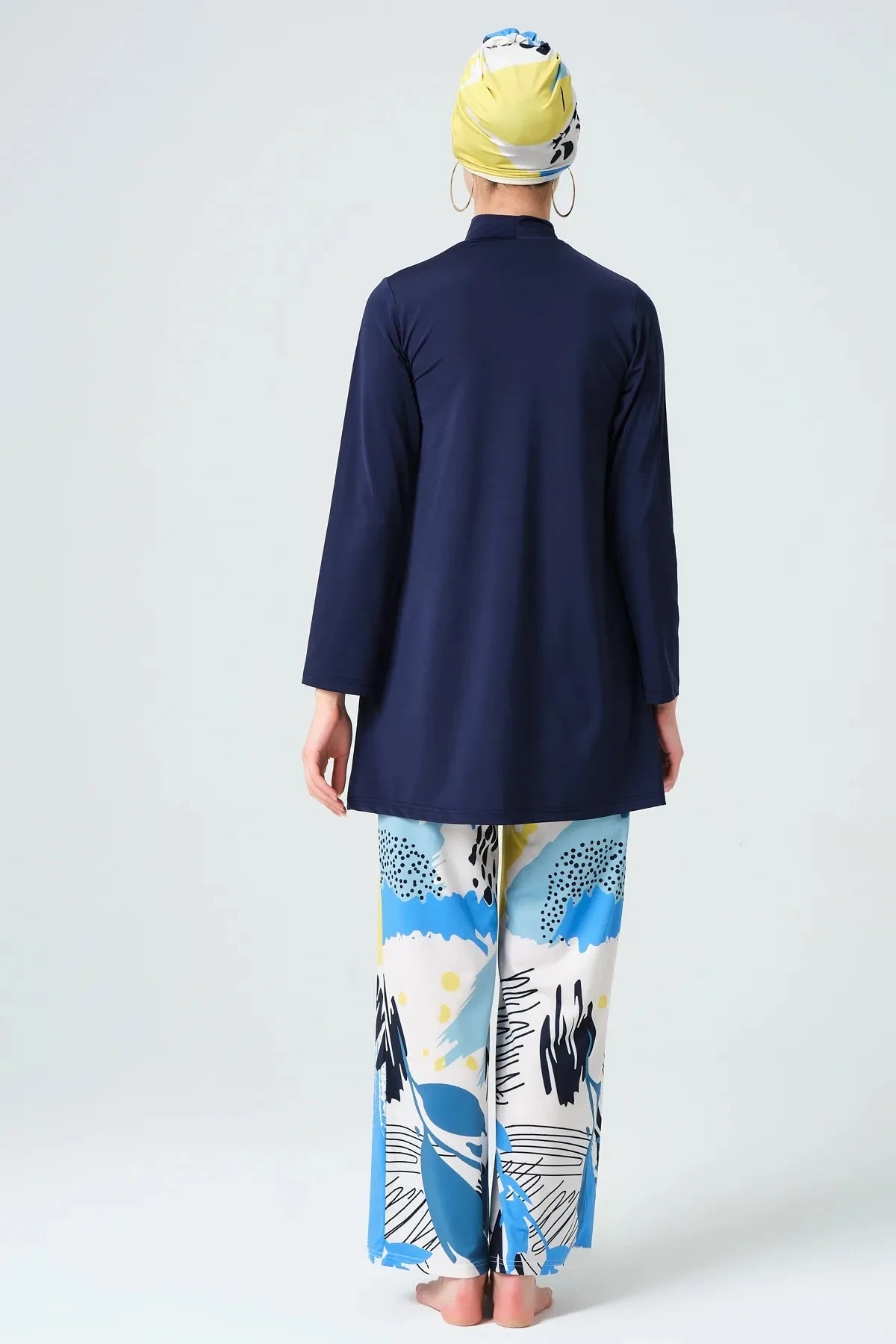 Model in navy modest swimwear set with abstract print pants, back view.
