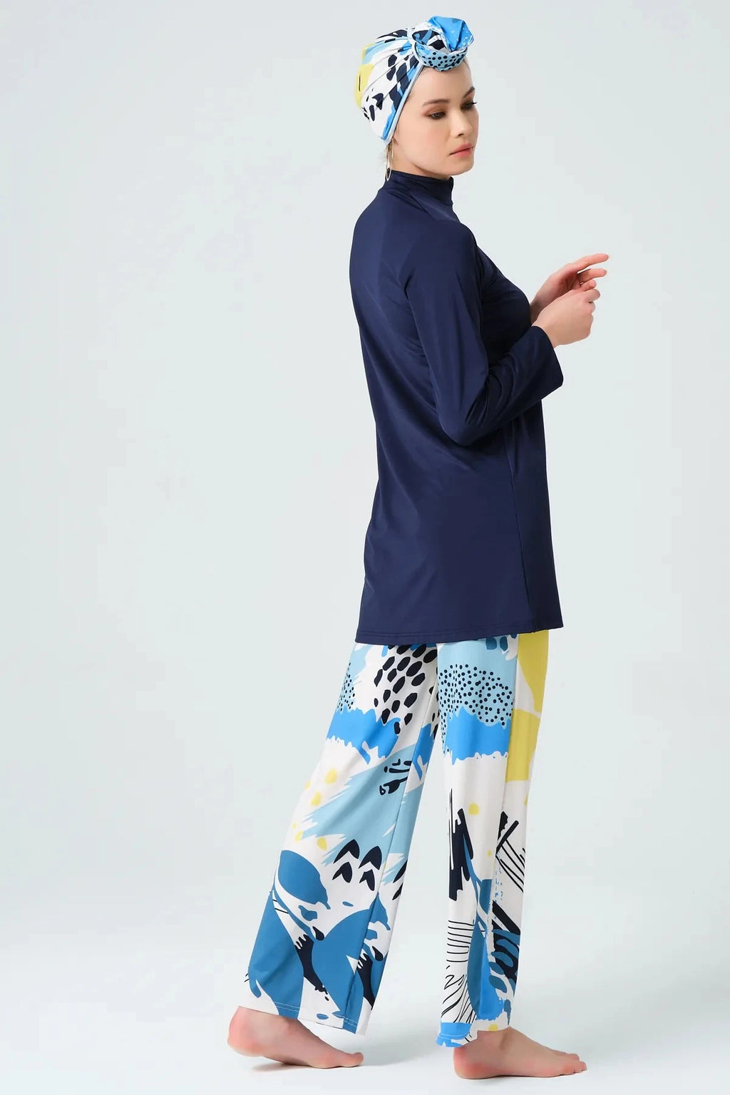 Model in navy modest swimwear set with abstract print pants, side view.