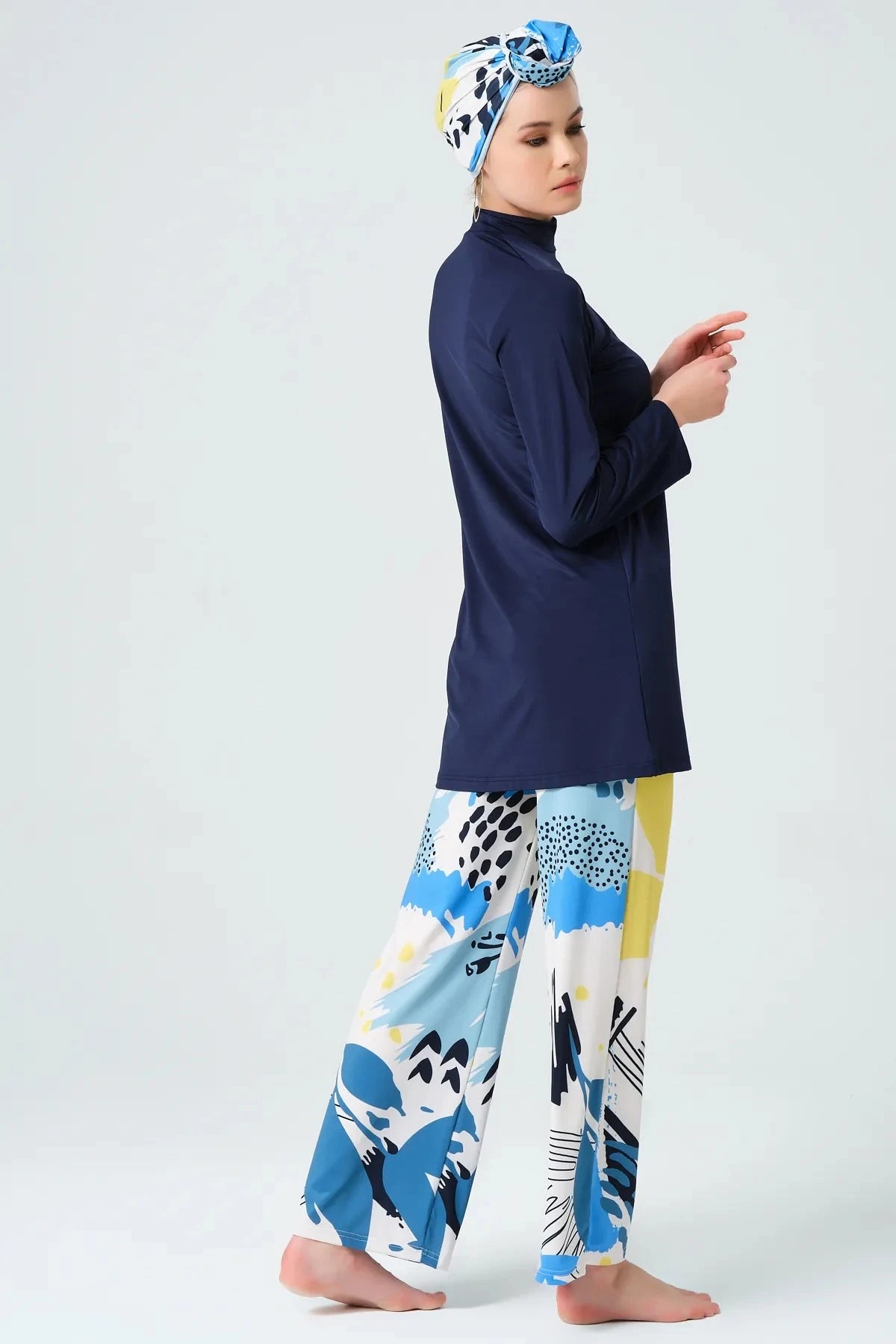 Model in navy modest swimwear set with abstract print pants, side view.