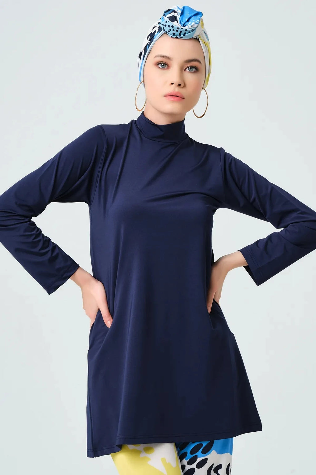 Close-up of model wearing navy tunic and abstract print headscarf.