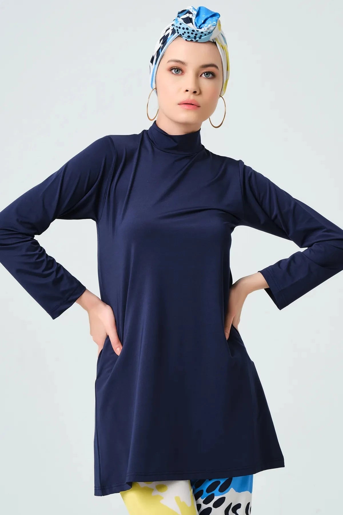 Close-up of model wearing navy tunic and abstract print headscarf.