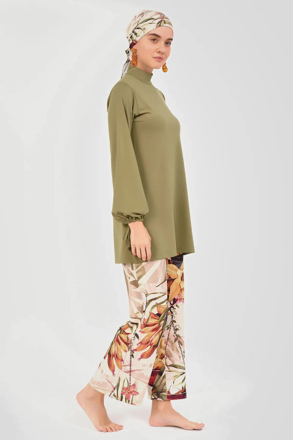 Side profile of model in olive green modest swimwear with printed pants.
