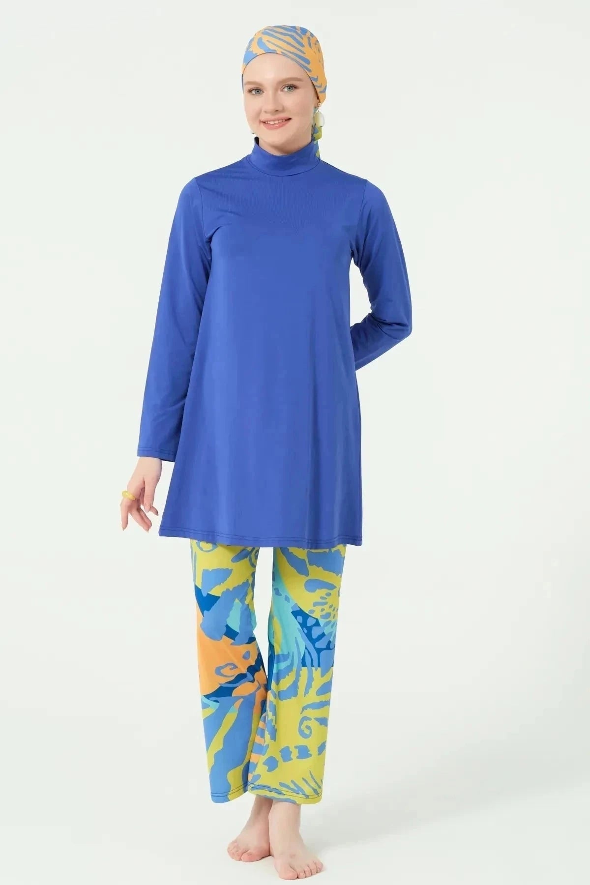 Model in blue modest swim top and abstract print pants.