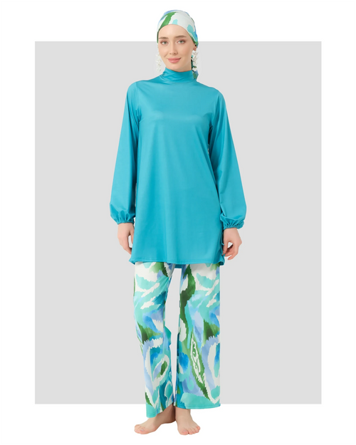 Woman in turquoise modest swimwear set with printed pants, front view.