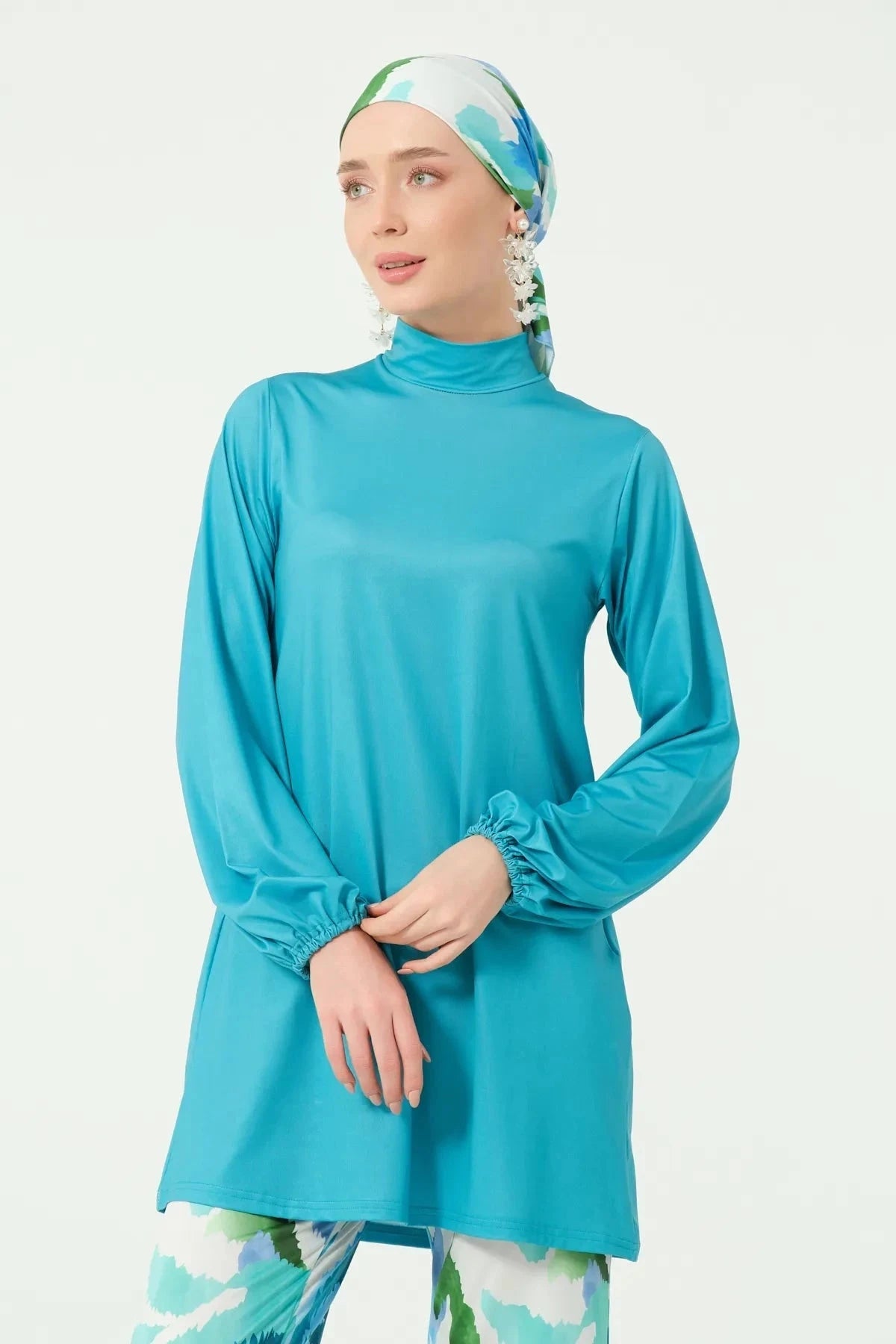 Close-up of turquoise modest swimwear tunic and printed headscarf.