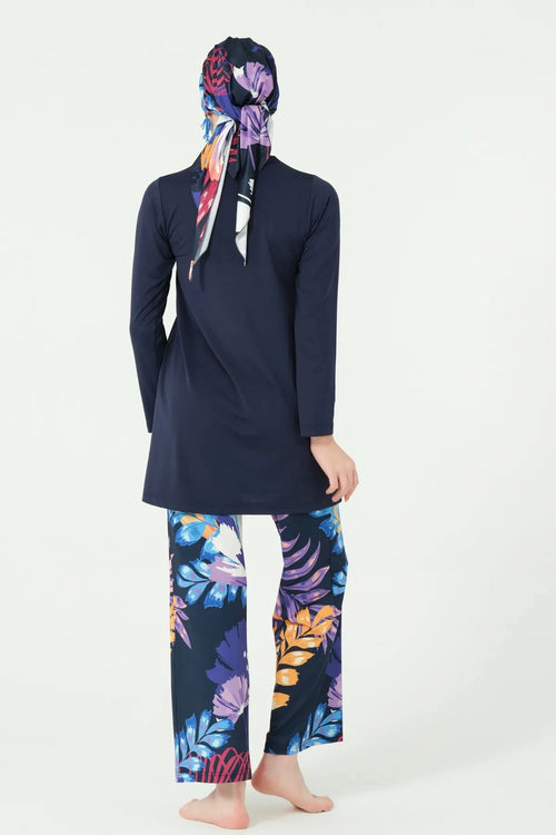 Back view of woman wearing navy modest swimwear and printed headscarf.