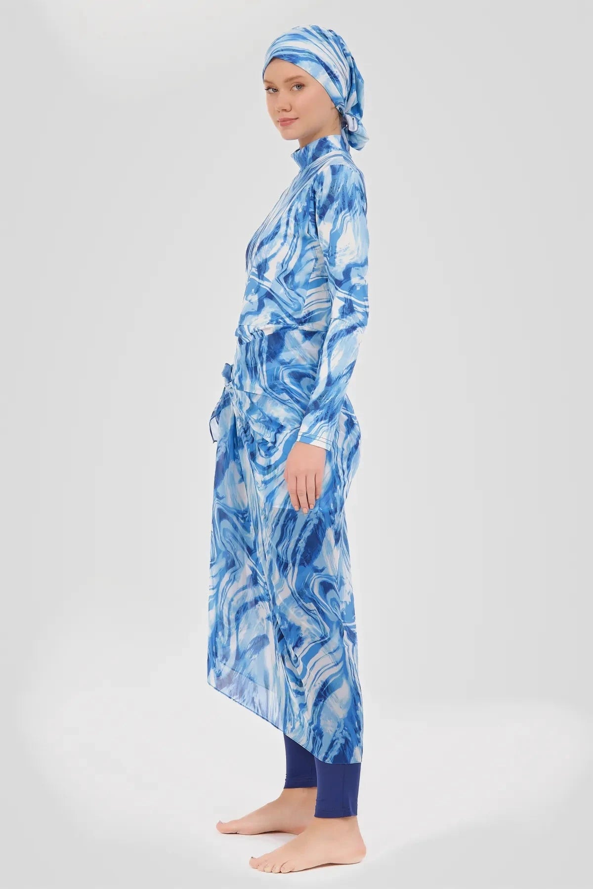 Woman in indigo ocean wave print modest sarong and swimwear set side view