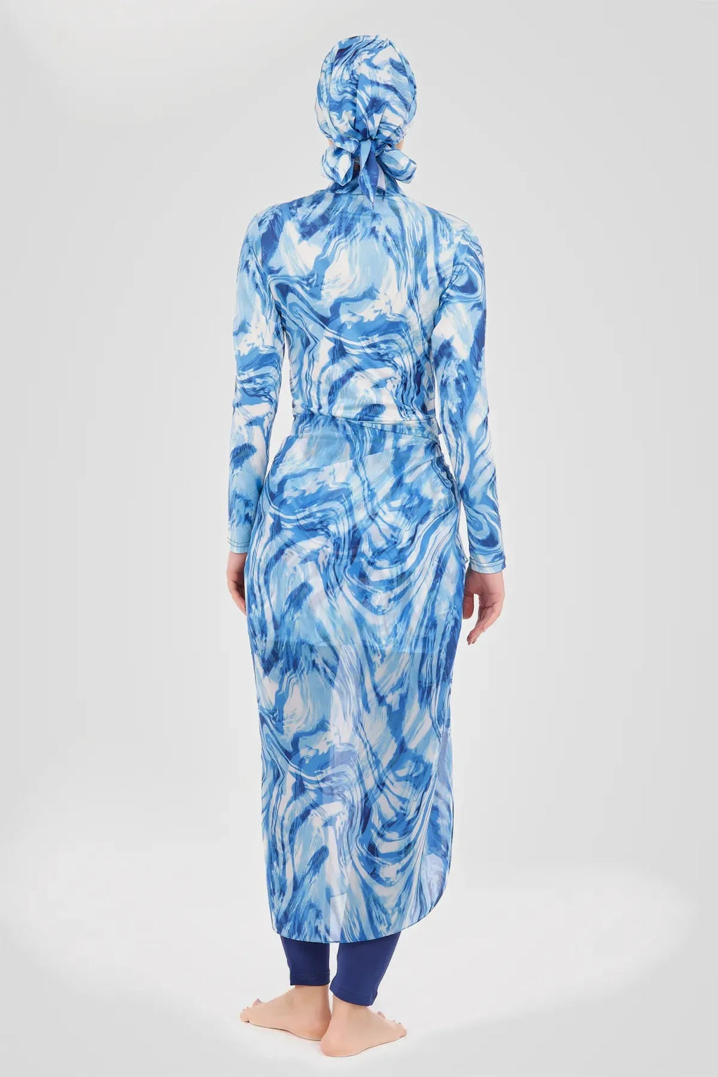Woman in indigo ocean wave print modest sarong and swimwear set back view