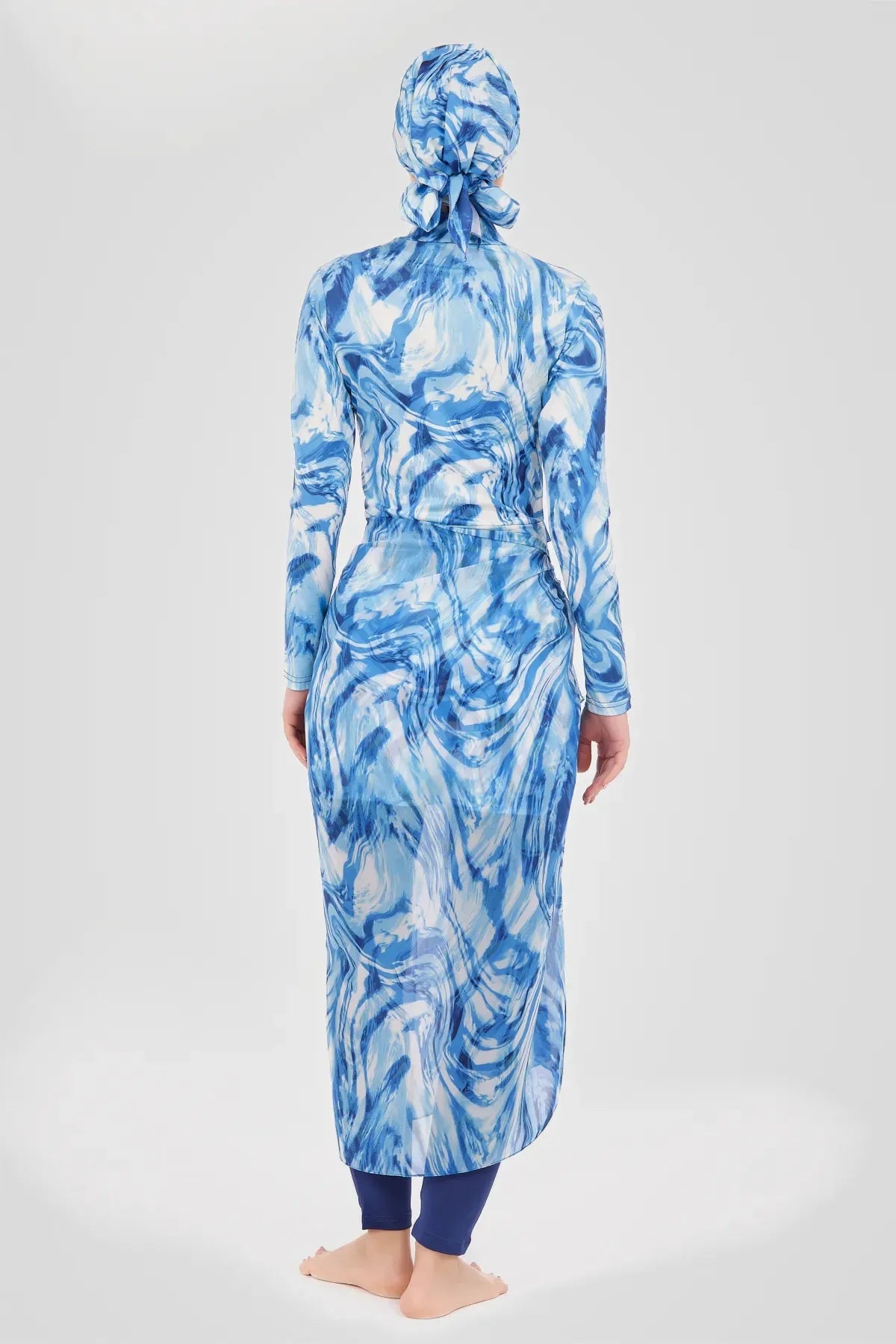 Woman in indigo ocean wave print modest sarong and swimwear set back view
