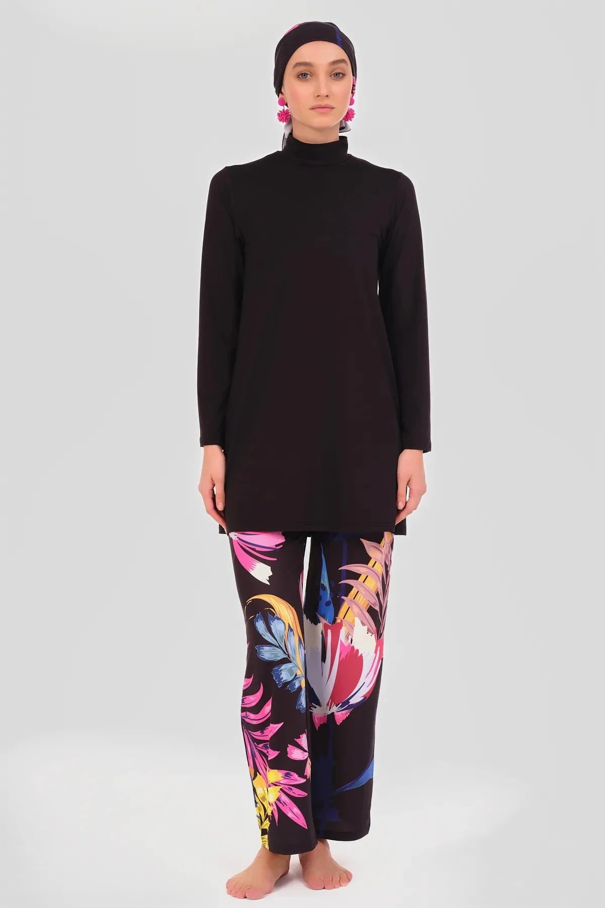 Model in black tunic, floral pants, and headscarf, full front view.