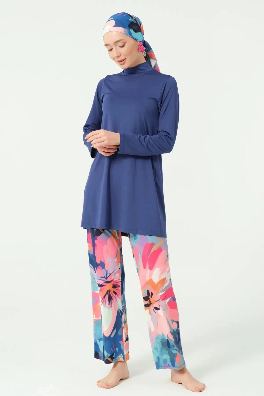 Woman in indigo floral modest swimwear set, looking down, hands clasped.