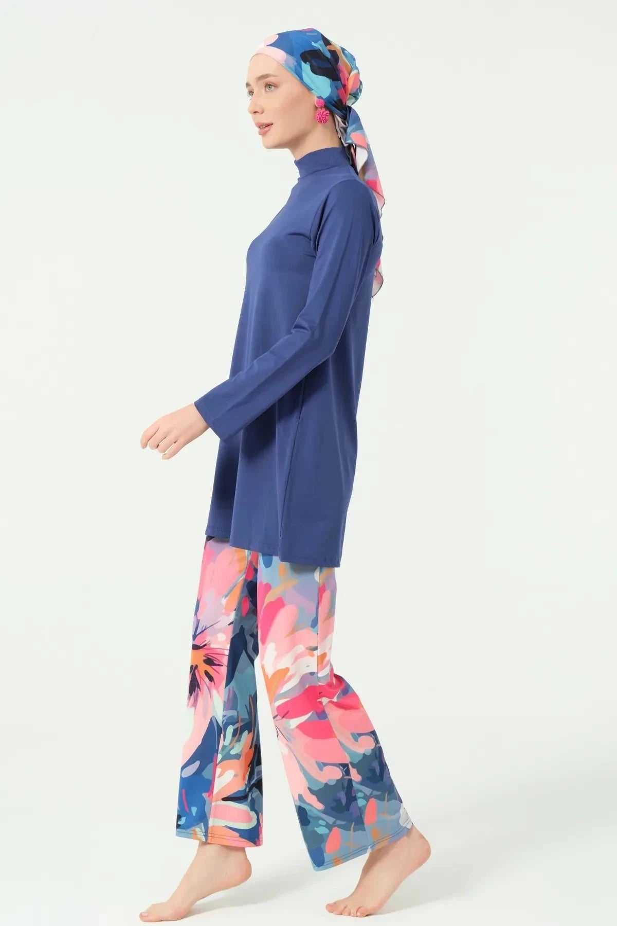 Side view of woman walking in indigo floral modest swimwear set.