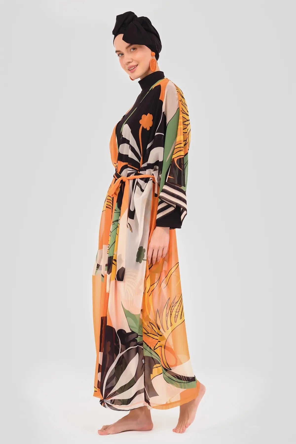 Model in orange floral kimono and black modest swimwear side view.