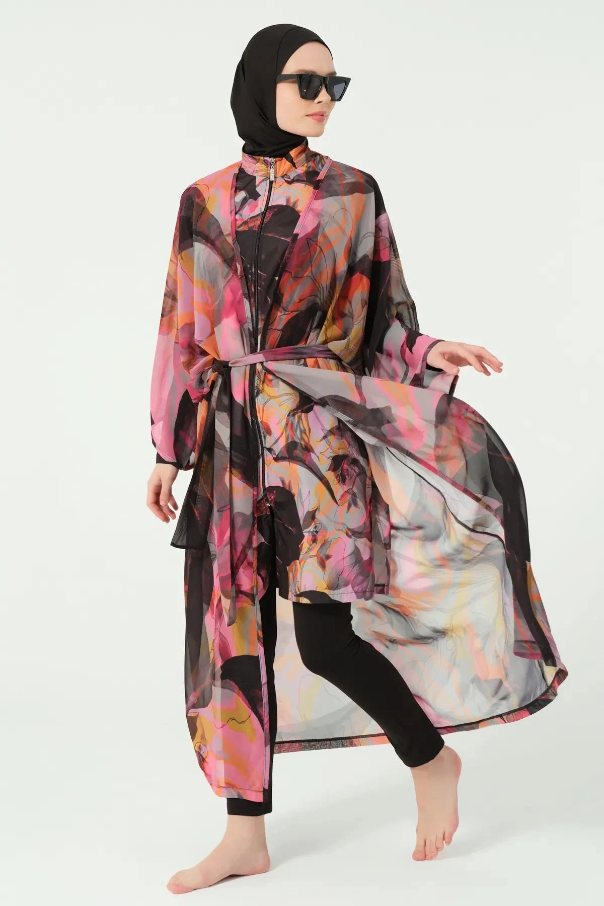Woman in vibrant abstract print kimono cover-up, black leggings, side pose.