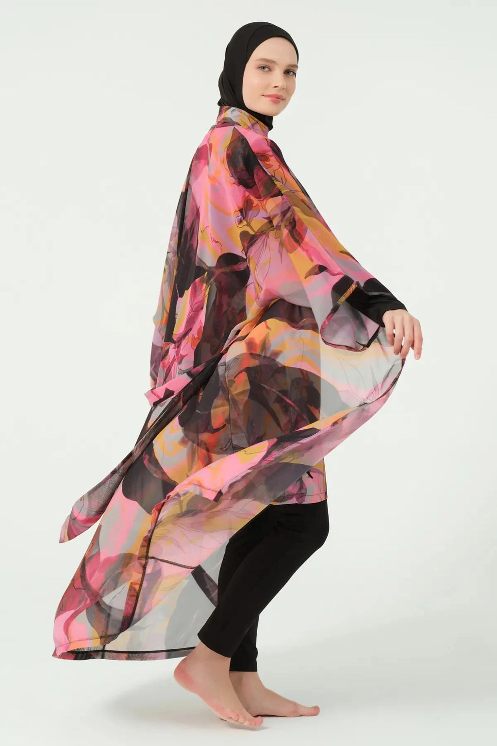 Woman in vibrant abstract print kimono cover-up, side view, fabric flowing.