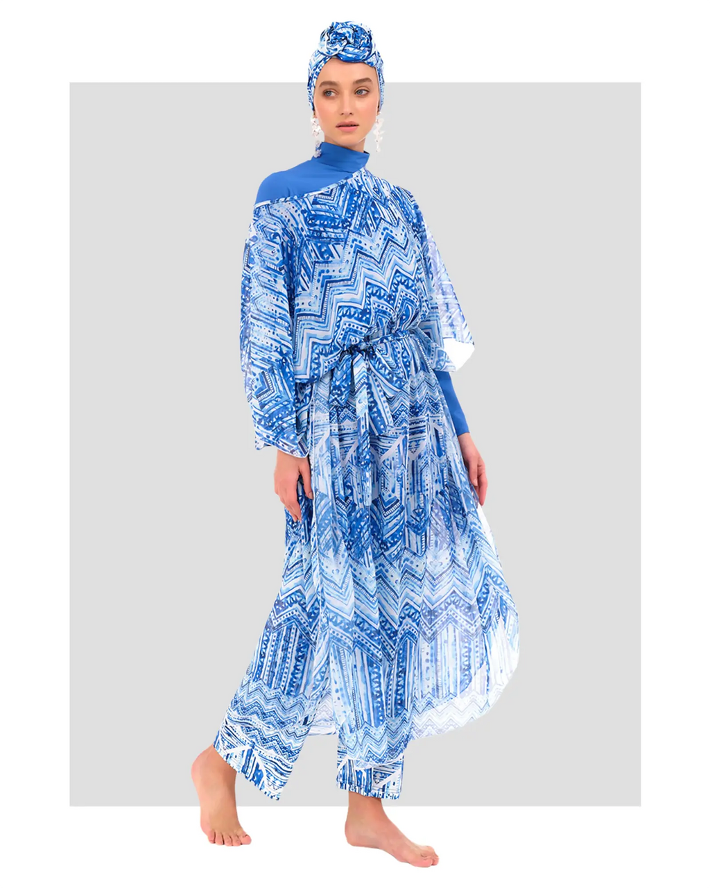 Model in blue modest swimwear with sheer patterned kimono and headscarf.