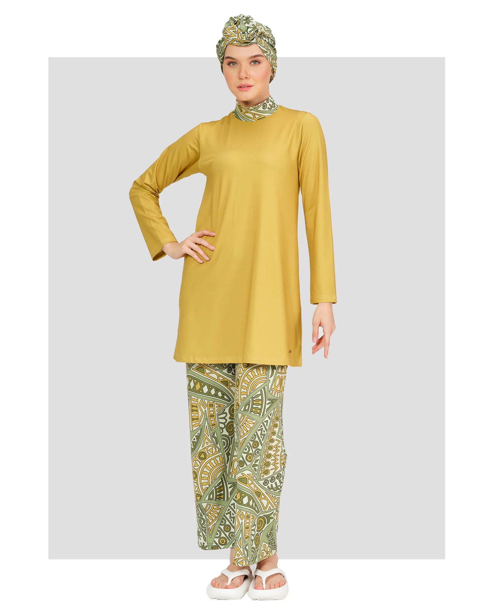 Model in mustard yellow top and green patterned modest swimsuit front view.
