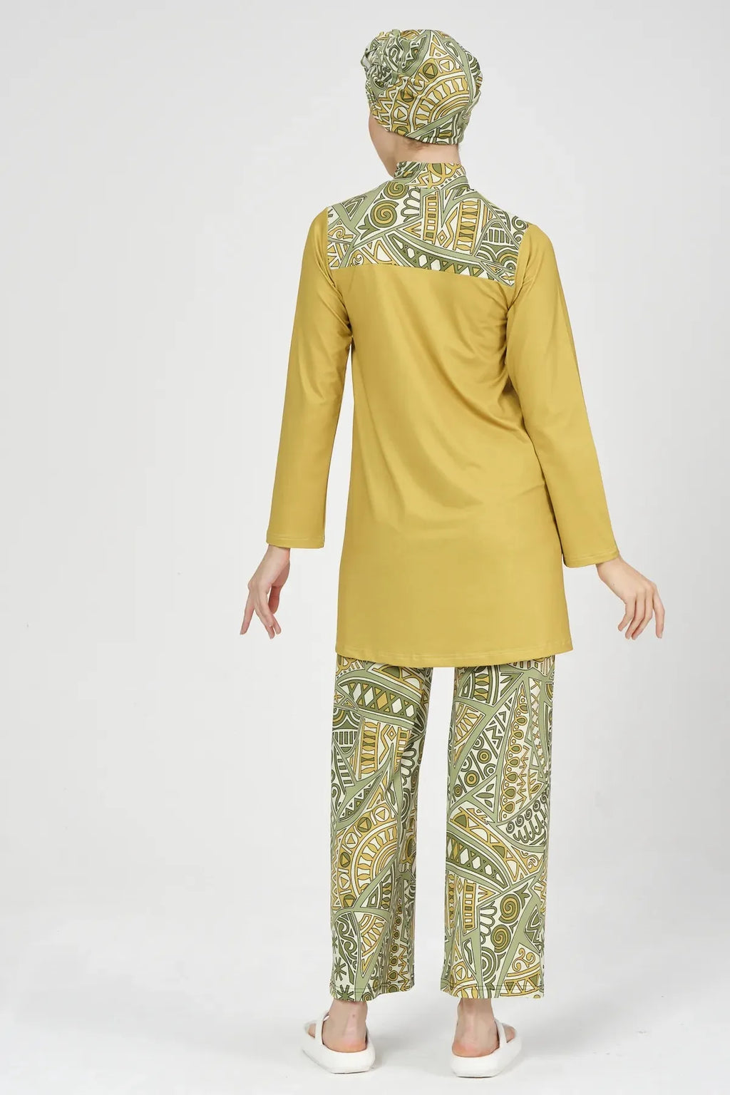 Model wearing mustard yellow and green patterned modest swimsuit from back.