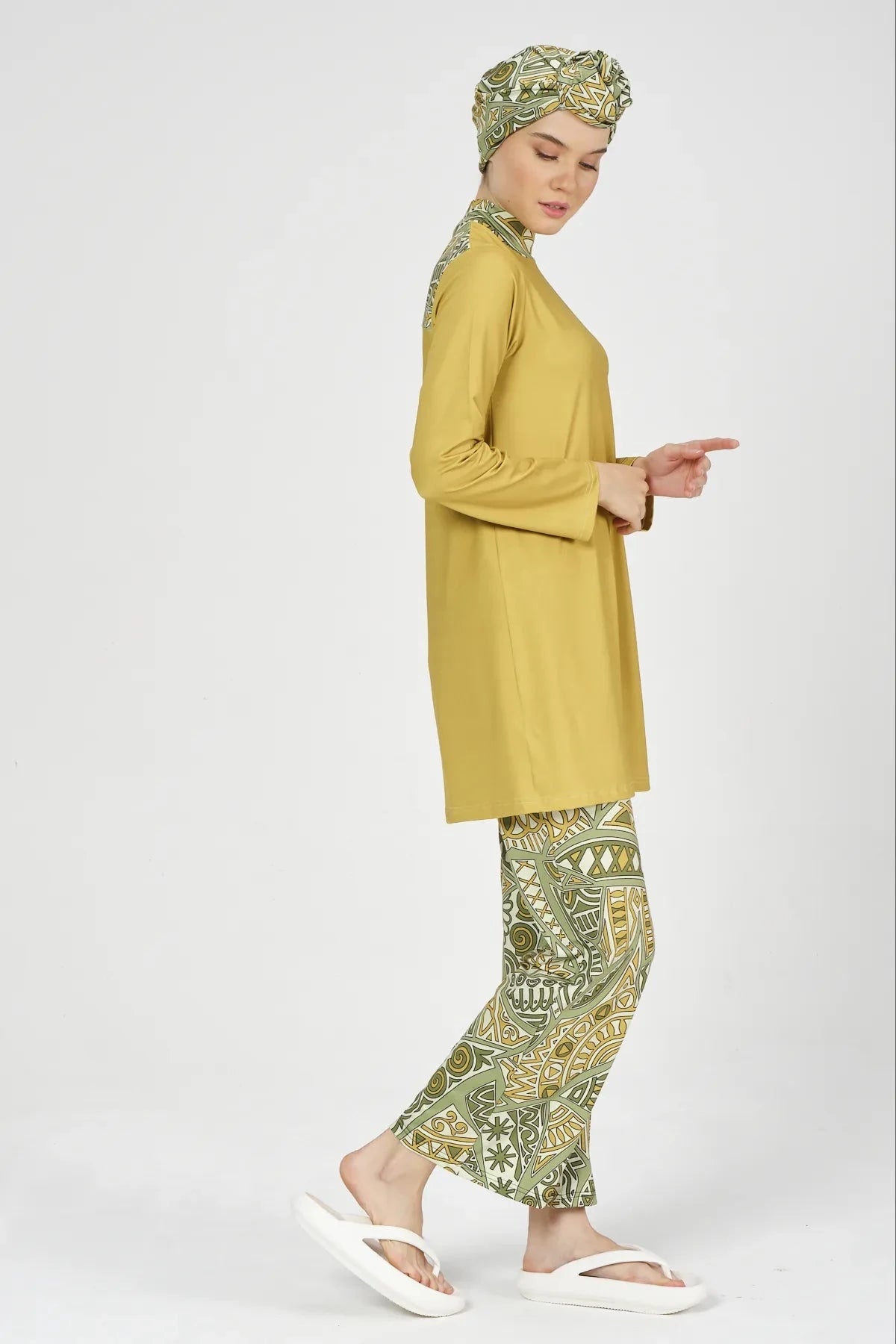 Side profile of model in mustard yellow and green patterned modest swimsuit.