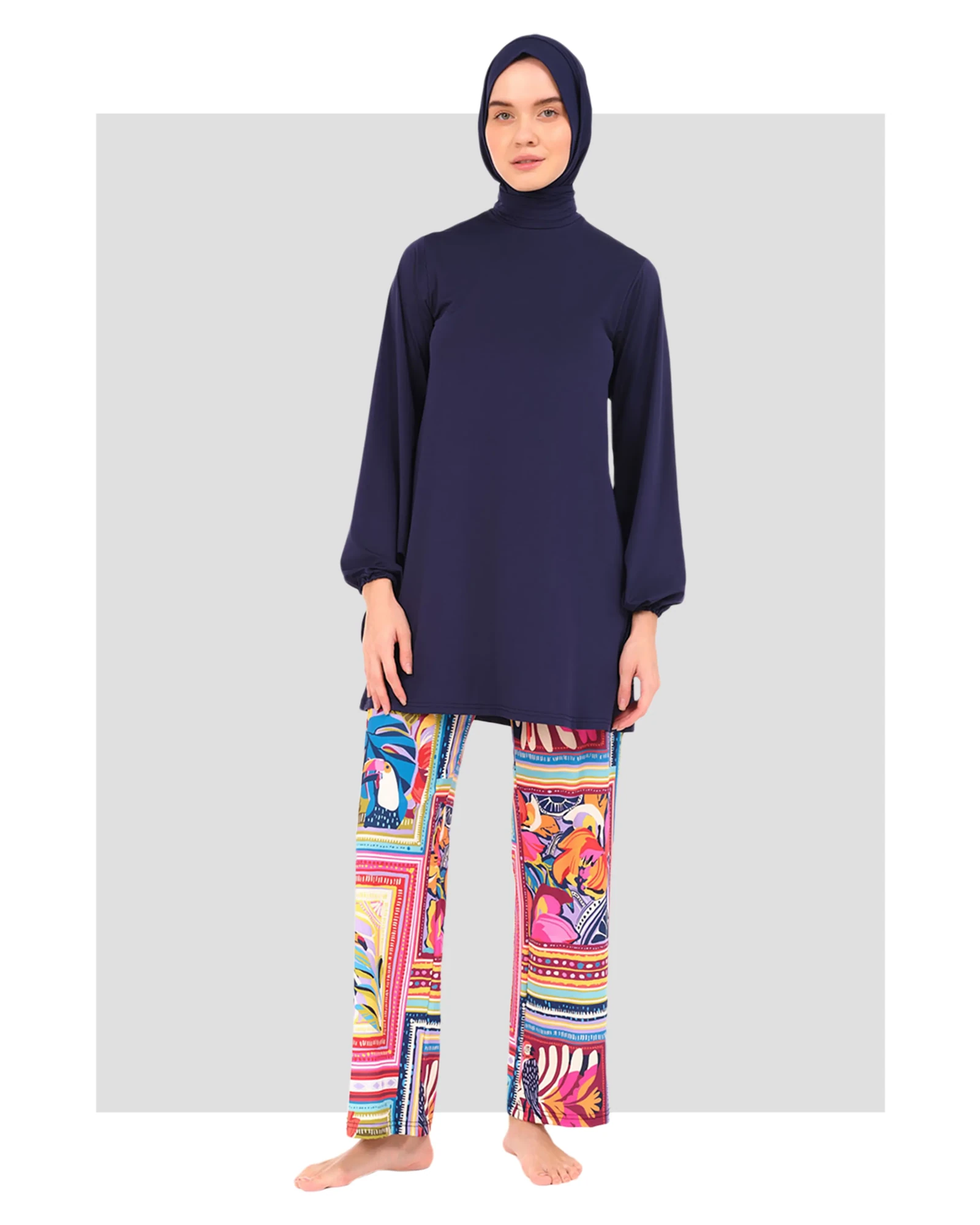 Model in navy tunic and vibrant tropical print swim pants, front view.