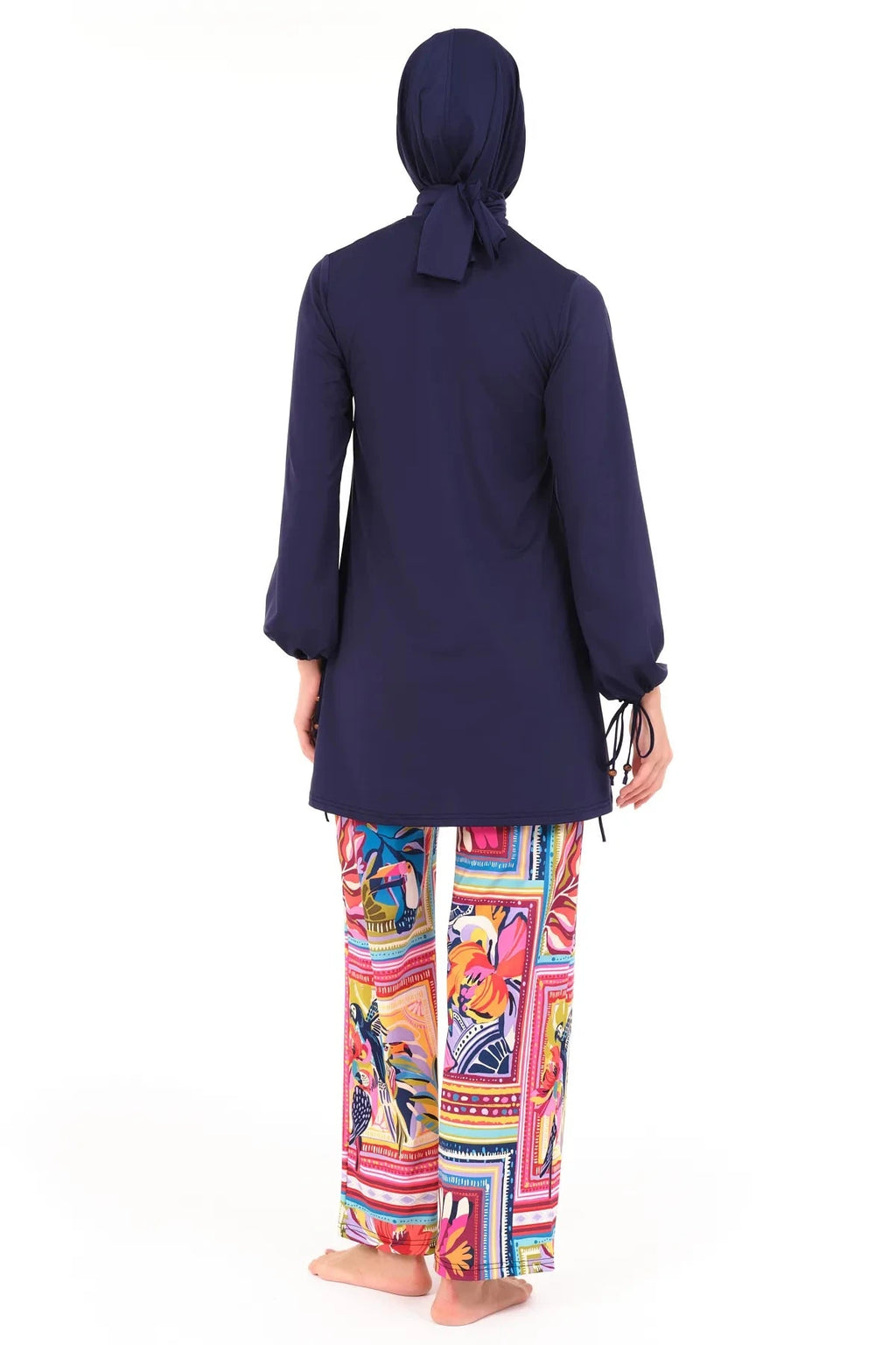 Model in navy tunic and vibrant tropical print swim pants, back view.