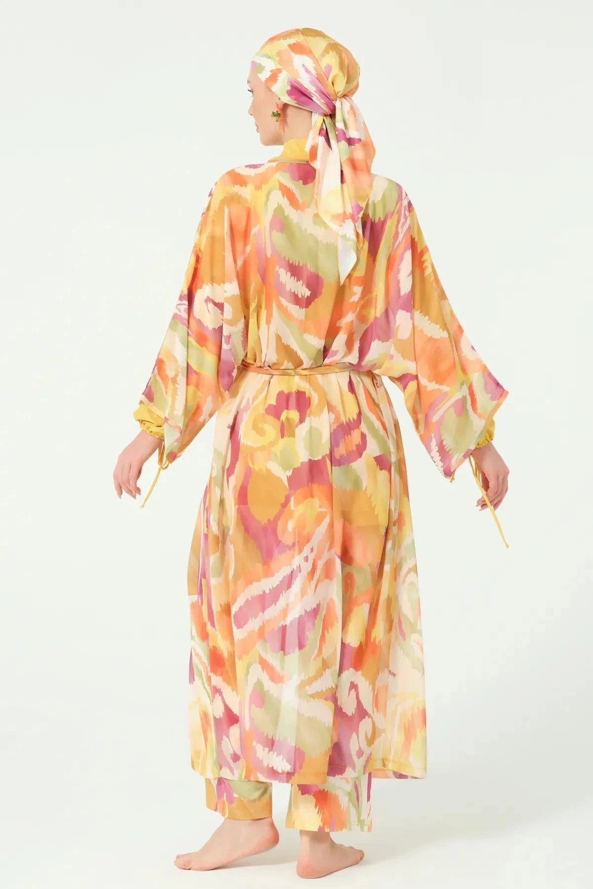 Back view of woman wearing golden sunset sheer kimono with belt.