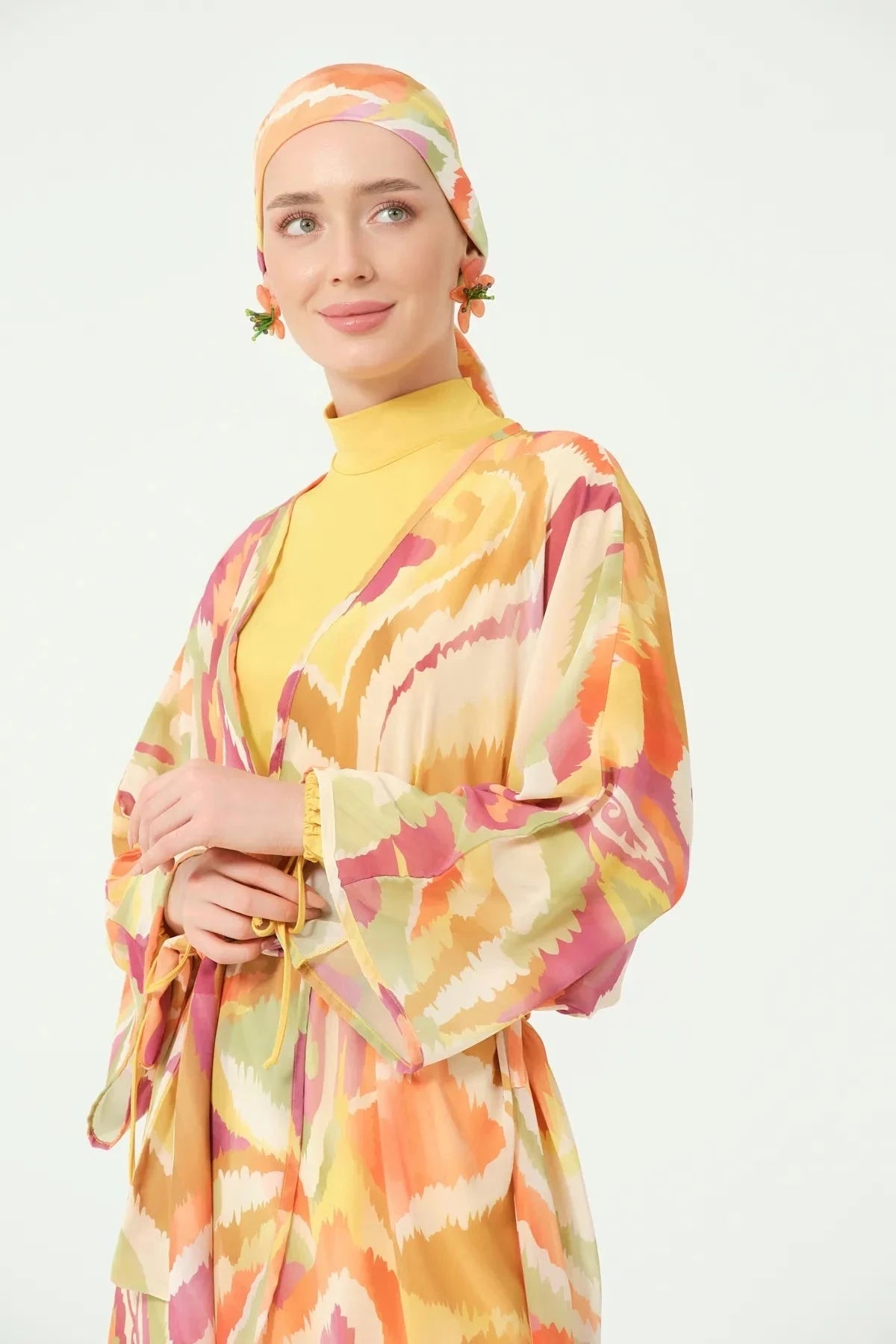 Close-up of woman in golden sunset sheer kimono and head covering.