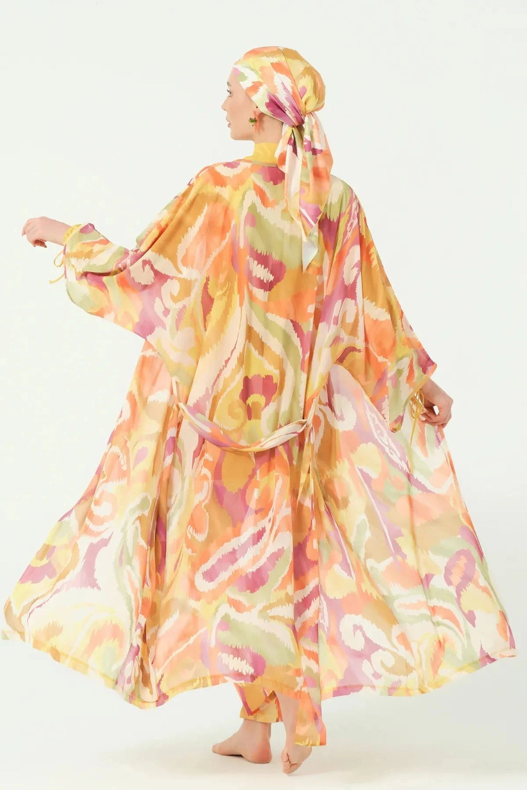 Woman turning in golden sunset sheer kimono with flowing fabric.