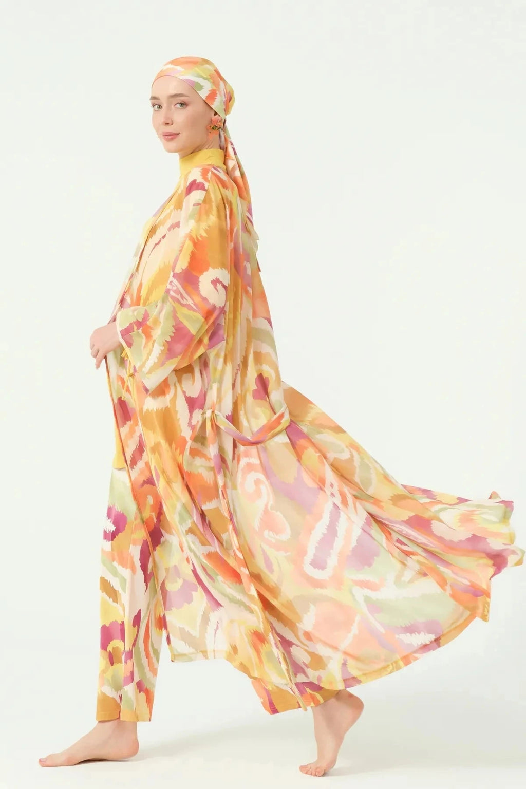 Side view of woman in golden sunset sheer kimono with flowing fabric.